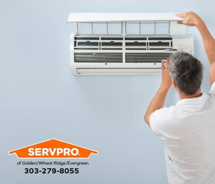 A person is cleaning an air conditioning system.