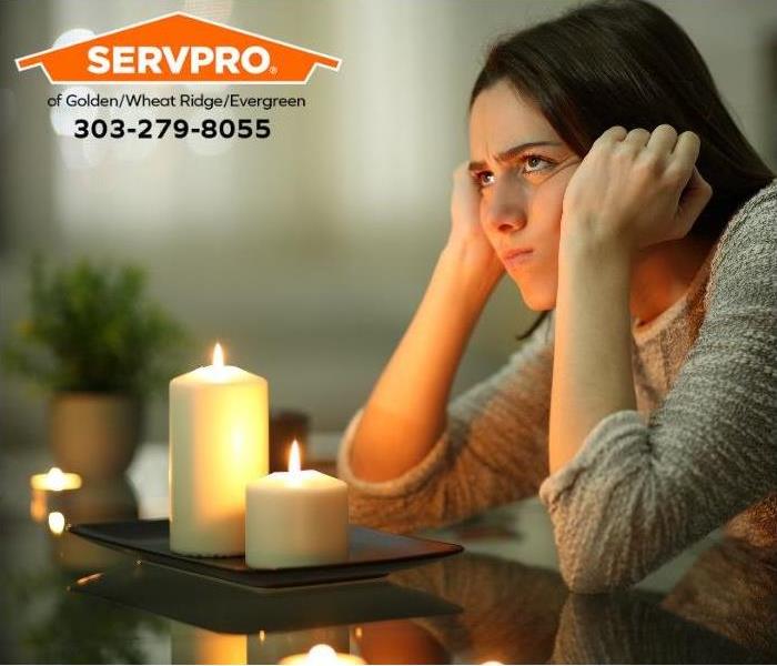 A frustrated person sits at a table lit by candles. 